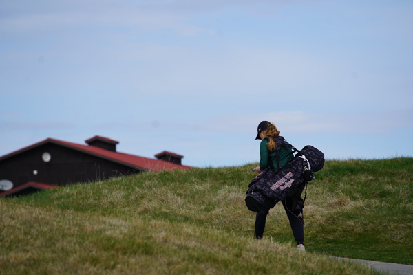 Montana Tech women's golf player carrying her clubs